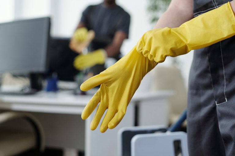 Person putting on rubber gloves before cleaning an office space