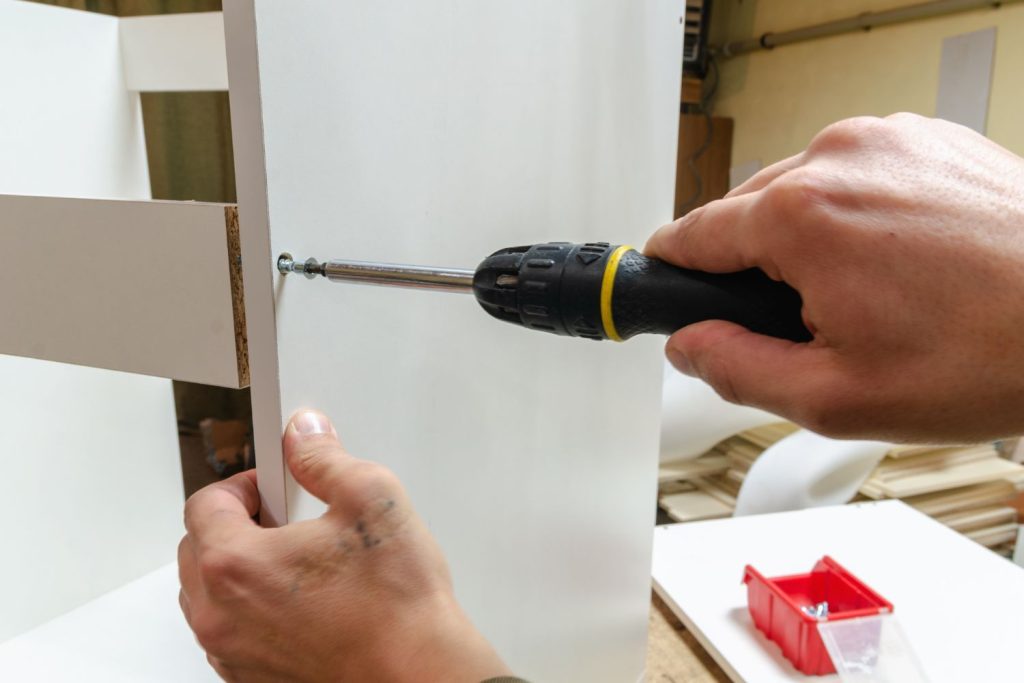man screwing furniture panel together