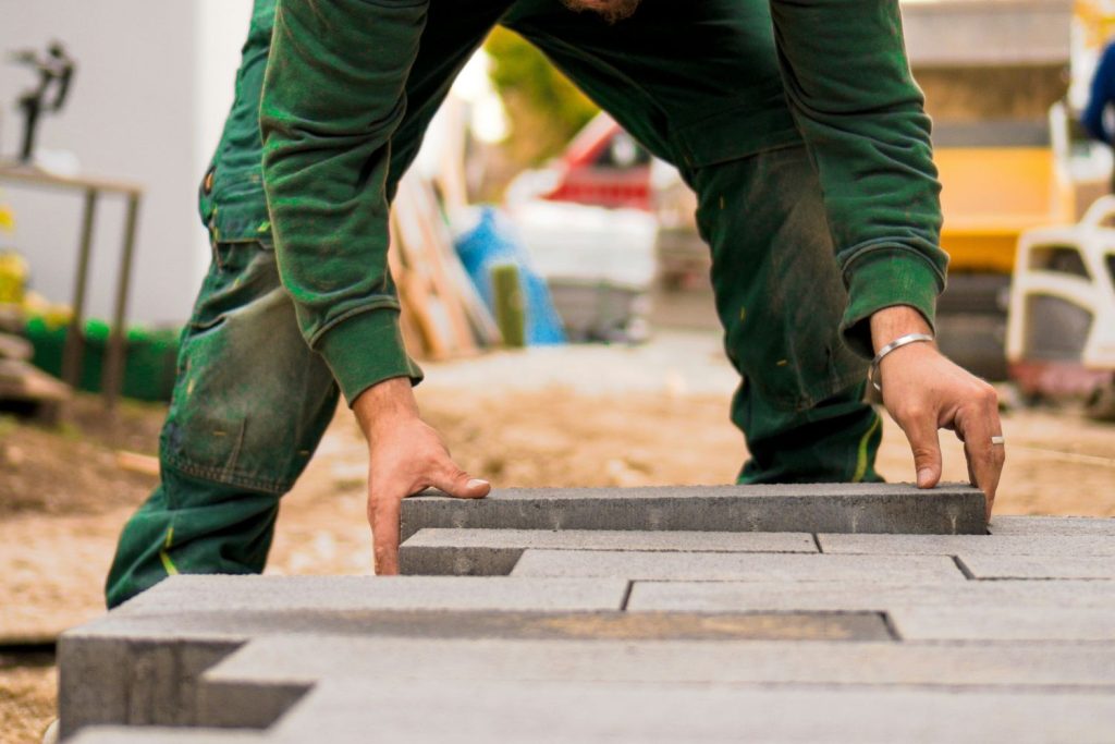 man laying paving slabs in garden