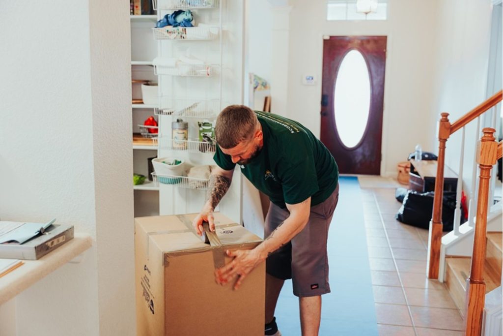 man sealing cardboard box in removals process
